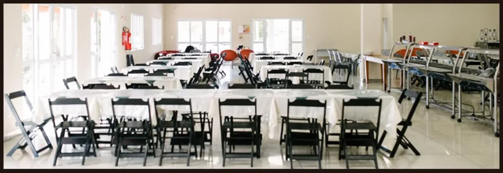 Salão amplo montado para um evento com mesas e cadeiras